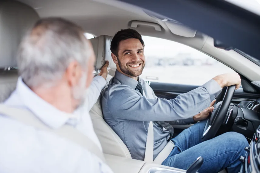 A caregiver driving an older client to an appointment with a reassuring smile.